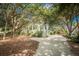 Charming exterior with a stone driveway, lush trees and professional landscaping creating a serene and welcoming curb appeal at 8869 Marsh Aire Ln, Edisto Island, SC 29438