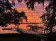 Tranquil sunset over water featuring a private dock, a covered gazebo, and a boat under a vibrant sky at 119 Riverland Dr, Charleston, SC 29412