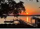 Sunset view of a private dock, a boat and tranquil water; the sky is ablaze with orange and pink hues at 119 Riverland Dr, Charleston, SC 29412