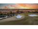 Scenic aerial view of a golf course with manicured greens, sand traps, and a small pond at sunset at 15 Watroo Pt, Daniel Island, SC 29492