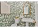 Elegant powder room with floral wallpaper, decorative mirror, and pedestal sink at 161 Marsh Hawk Ln, Kiawah Island, SC 29455