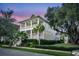 Charming two-story home featuring double porches, a landscaped yard with palm trees, and a classic coastal design at twilight at 164 River Green Pl, Charleston, SC 29492