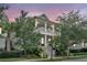 Elegant two-story light blue home featuring double balconies, a welcoming staircase, and lush landscaping at 164 River Green Pl, Charleston, SC 29492