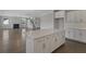 Bright kitchen with white cabinets, an island, and hardwood floors, leading to the living room and staircase at 2006 Riverbend Dr, Charleston, SC 29412