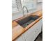 Close up of a sink with dark basin set in wooden countertops beneath a window with blinds at 209 E 4Th S St, Summerville, SC 29483