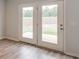 Double doors open to a large grassy backyard area with mature trees and a concrete patio at 223 West Bradford Pointe Dr, Summerville, SC 29486