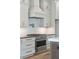 Close up of Kitchen stove, hood, white cabinets, and stylish backsplash at 2982 Lodge Berry Ln, Johns Island, SC 29455