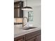 Close-up of kitchen sink and faucet with quartz countertop and dark cabinets in a modern design at 2982 Lodge Berry Ln, Johns Island, SC 29455