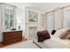 Comfortable bedroom featuring a decorative fireplace, plantation shutters, and elegant decor at 32 Tradd St, Charleston, SC 29401