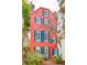Striking three-story home with coral exterior, blue shutters, and inviting courtyard at 32 Tradd St, Charleston, SC 29401