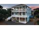 View of the three-story blue house featuring multiple porches, stylish railings, and ground level access at 74 Sandbar Ln, Folly Beach, SC 29439