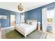 Serene main bedroom with blue accent wall, natural light, and a glimpse of the en-suite bathroom at 74 Sandbar Ln, Folly Beach, SC 29439