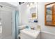Bright bathroom featuring a shower with a blue curtain, vanity, and a decorative mirror and an accent window at 807 Treeloft Trce, Seabrook Island, SC 29455