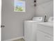 Well-lit laundry room with a window, white washer and dryer, and upper shelving at 9998 Winged Elm St, Ladson, SC 29456