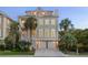 Inviting three-story house with a two-car garage, framed by palm trees and showcasing a grand entrance at 10 Ocean Point Dr, Isle of Palms, SC 29451