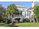 Elegant gray home featuring a screened porch, bay window, and lush landscaping at 10 Ocean Point Dr, Isle of Palms, SC 29451
