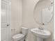 A half bathroom with a white toilet, pedestal sink, and an oval mirror at 105 Pen Shell St, Summerville, SC 29485