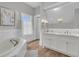 Well-lit bathroom with a large mirror, double sinks and a soaking tub with a handheld shower at 112 Ocean Blvd, Isle of Palms, SC 29451