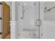 A white bathroom has an all glass shower, a wooden door, and decorative tiling on the shower floor at 112 Ocean Blvd, Isle of Palms, SC 29451