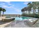 This luxurious pool area overlooks the ocean and features a pool, hot tub, and palm trees at 112 Ocean Blvd, Isle of Palms, SC 29451