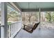 Relax on the porch swing overlooking a picturesque scene surrounded by trees, with a light blue paneled ceiling at 135 Rapture Ln, Wando, SC 29492