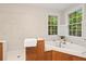 Bright bathroom featuring a soaking tub with jets, light tile, and two windows overlooking a private wooded lot at 140 Old Plantation Ln, Moncks Corner, SC 29461