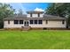 Back exterior of the two-story home with a well-maintained lawn, brick foundation and steps, and natural light at 140 Old Plantation Ln, Moncks Corner, SC 29461