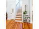 Charming hallway with hardwood floors leading to a stairway with wood accents and a decorative console table at 22 1/2 Mary St # A B C, Charleston, SC 29403