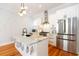 Modern kitchen with a marble island, stainless steel appliances, white cabinetry, and hardwood flooring, illuminated by a stylish light fixture at 22 1/2 Mary St # A B C, Charleston, SC 29403