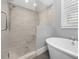 A modern bathroom featuring an open shower, standalone tub, tiled walls, and shuttered window at 2932 Old Drake Dr, Seabrook Island, SC 29455