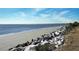 Picturesque oceanfront view showcasing a serene beach with natural rock formations and vegetation at 2932 Old Drake Dr, Seabrook Island, SC 29455