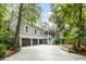 Stunning exterior showcasing the home's architectural design, three-car garage, and lush, mature landscaping at 2932 Old Drake Dr, Johns Island, SC 29455