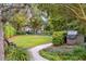 Lush backyard featuring a winding pathway, green lawn, mature trees, and a covered outdoor grill at 67 Legare St # 305, Charleston, SC 29401
