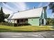 A beautiful green barn with a metal roof stands proudly on a well-manicured lawn and a partial hedge row at 116 Snow St, Summerville, SC 29486