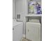 Bright laundry room features a white washer, dryer and water heater on a shelf, and neutral tile flooring at 1203 Meadow Park Ln # B, Mount Pleasant, SC 29464