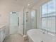Bright bathroom featuring a soaking tub, glass shower, and large window with white wood blinds at 219 Clearblue Loop, Summerville, SC 29486