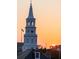 Majestic white clock tower with a backdrop of vibrant sunset colors at 23 Elliott St, Charleston, SC 29401