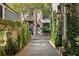 Picturesque walkway with stone pavers lined by verdant greenery leading towards a black iron gate at 23 Elliott St, Charleston, SC 29401