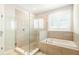 Bathroom boasts separate tiled shower and soaking tub next to a shuttered window for serene natural light at 236 River Martin Ct, Summerville, SC 29483