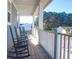 Covered porch with rocking chairs offers a relaxing outdoor space with views of the surrounding trees at 2613 Hatch Dr, Johns Island, SC 29455