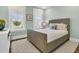 This bedroom shows a bed with a white rug and two windows with outdoor views and plantation shutters at 306 Autumn Azalea Way, Summerville, SC 29486