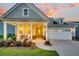 Inviting home with charming front porch, neat landscaping, and a two-car garage at sunset at 306 Autumn Azalea Way, Summerville, SC 29486