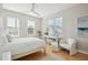 Bright bedroom with large windows, modern ceiling fan, wood floors, exercise bike and white furniture at 33 Calhoun St # 218, Charleston, SC 29401