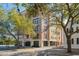 Exterior of a multi-story brick condo building with lush trees and professional landscaping at 33 Calhoun St # 218, Charleston, SC 29401