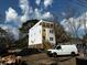 Three-story home under construction with a white exterior, wooden stairs, and a utility van in the driveway at 515 Joseph St, Charleston, SC 29412