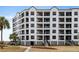 Multi-story condo building featuring multiple balconies, palm trees and manicured grounds at 8000 Palmetto Dr # 103-A, Isle of Palms, SC 29451