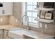 Farmhouse-style kitchen sink with a chrome faucet, tiled backsplash, and white countertops at 136 Fair Sailing Rd, Mount Pleasant, SC 29466
