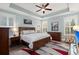 Well-lit bedroom with a tray ceiling, ceiling fan, light blue walls, white shutters, wood furniture, and a stylish rug at 2006 Barn Swallow Rd, Summerville, SC 29483