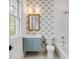 Bright bathroom featuring patterned wallpaper, a blue vanity, and a shower tub at 217 King George St, Daniel Island, SC 29492