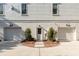 View of two-car garage with entry door, featuring a brick and concrete driveway and manicured shrubs at 217 King George St, Daniel Island, SC 29492